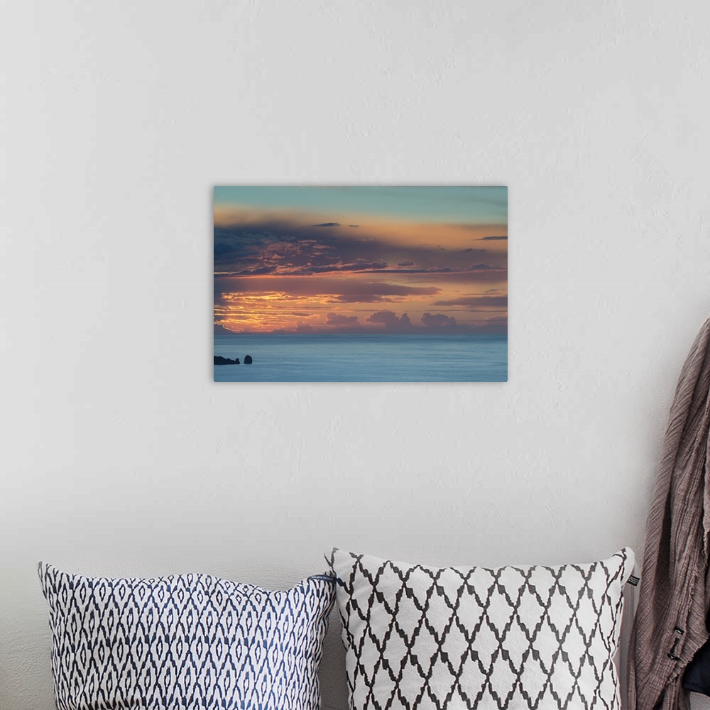 A bohemian room featuring Photograph of clouds and ocean boulders casting silhouettes from the sun setting in the distance.