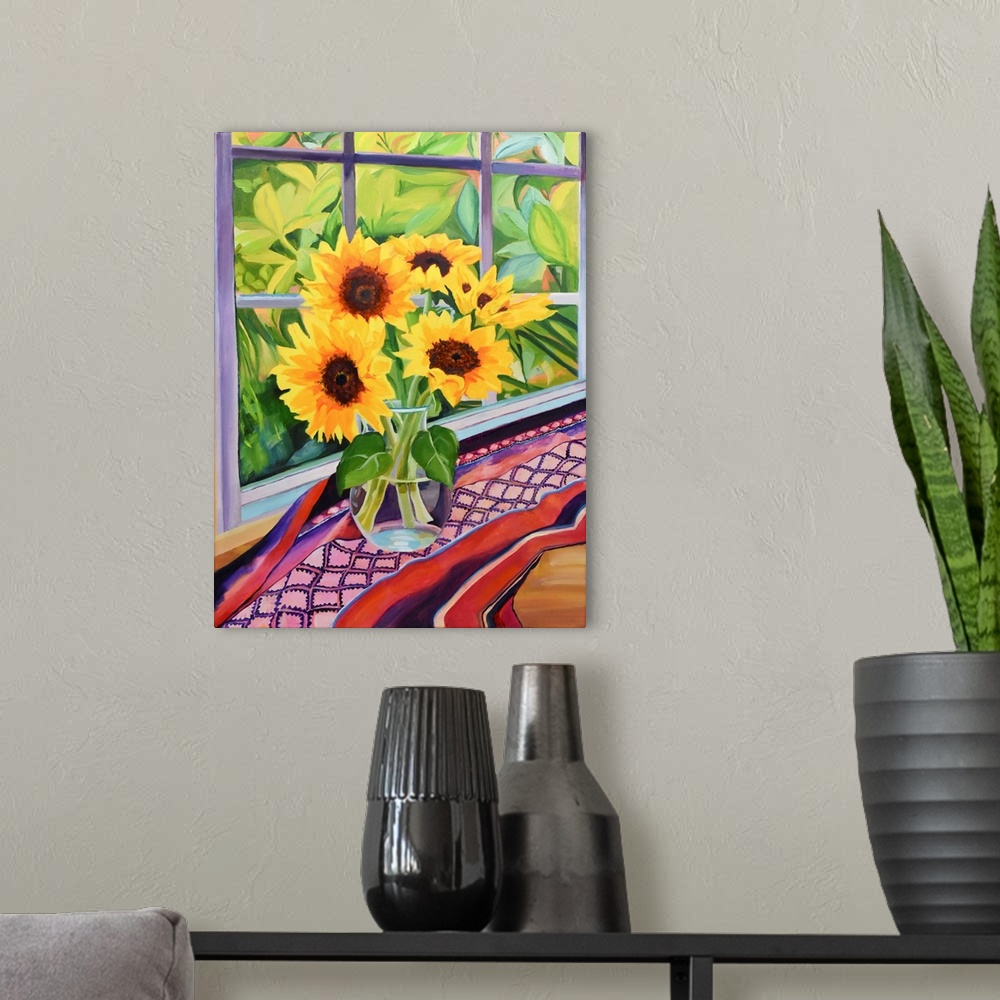 A modern room featuring Sunflowers in glass vase on table with plants visible through window.