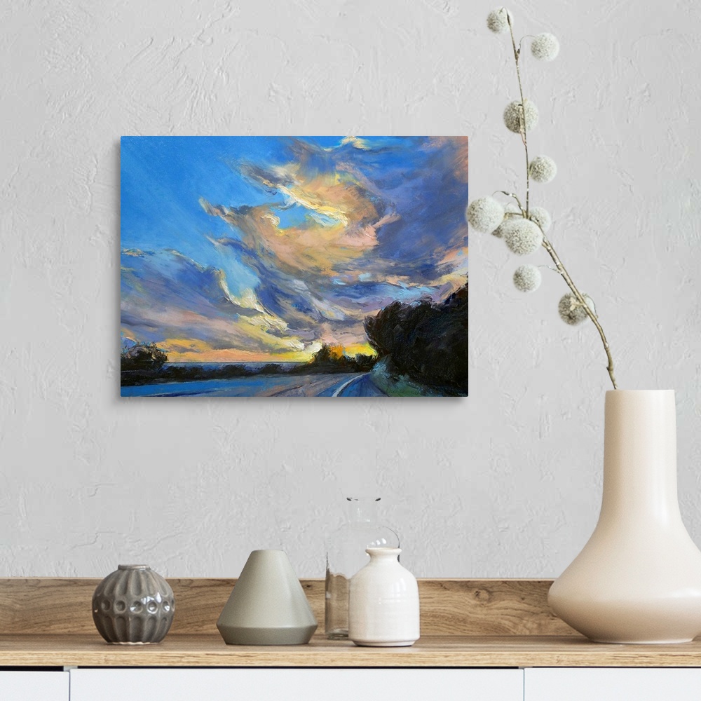 A farmhouse room featuring Horizontal painting on large canvas of a road leading into the sunset, beneath a sky of swirling ...