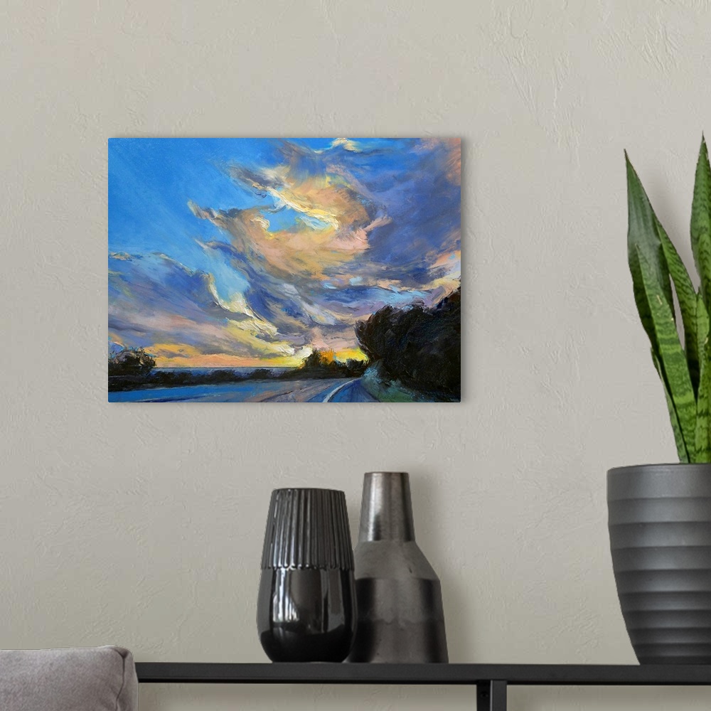 A modern room featuring Horizontal painting on large canvas of a road leading into the sunset, beneath a sky of swirling ...
