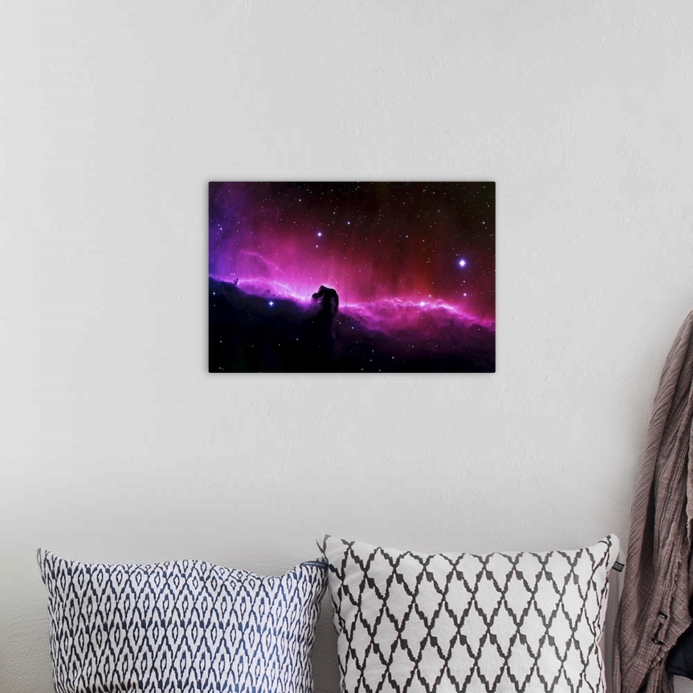 A bohemian room featuring Big wall art of a brightly colored nebula in the solar system with clouds that look like a horse'...