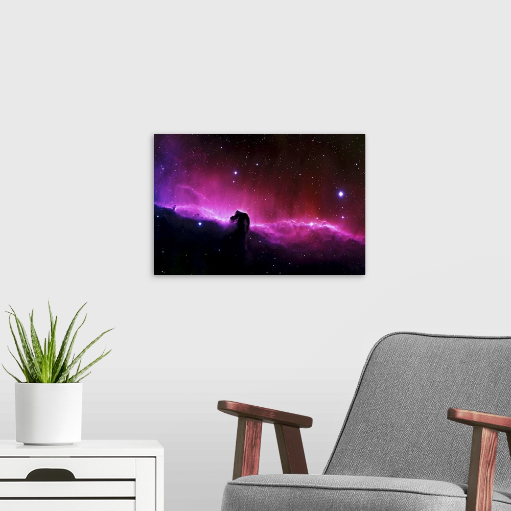A modern room featuring Big wall art of a brightly colored nebula in the solar system with clouds that look like a horse'...