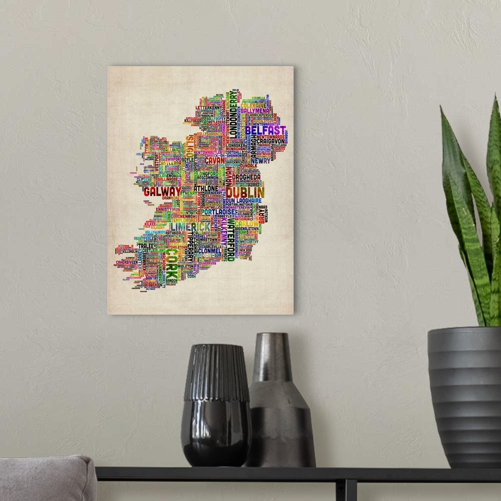 A modern room featuring Vertical, big canvas art of Ireland, composed of city names in multiple, bright colors, on a parc...