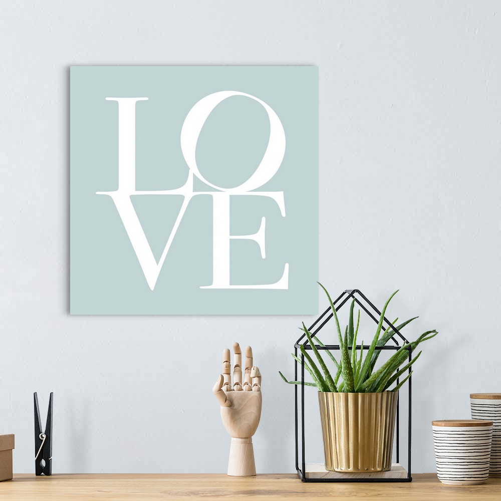 A bohemian room featuring LOVE, typography text art print and canvas print, with the word LOVE written against a duck egg b...