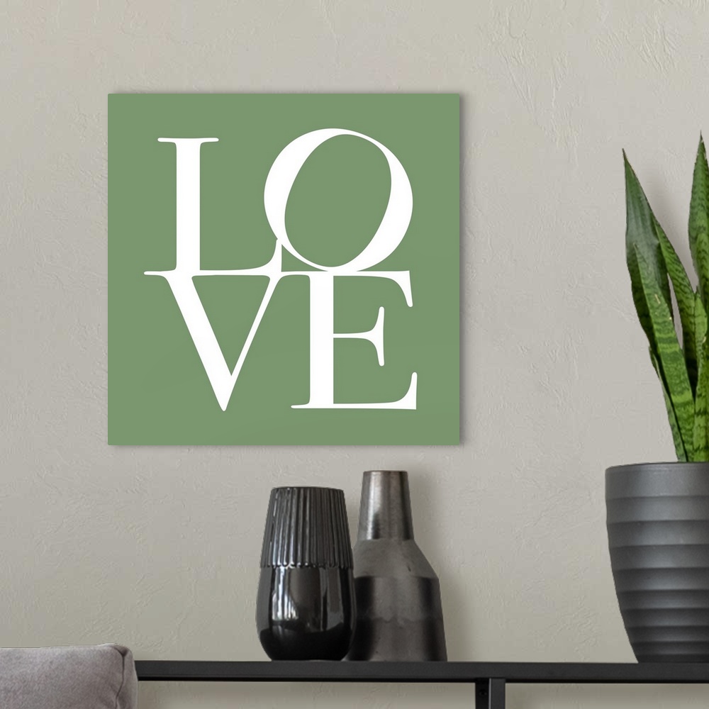 A modern room featuring LOVE, typography text art print and canvas print, with the word LOVE written against a green back...