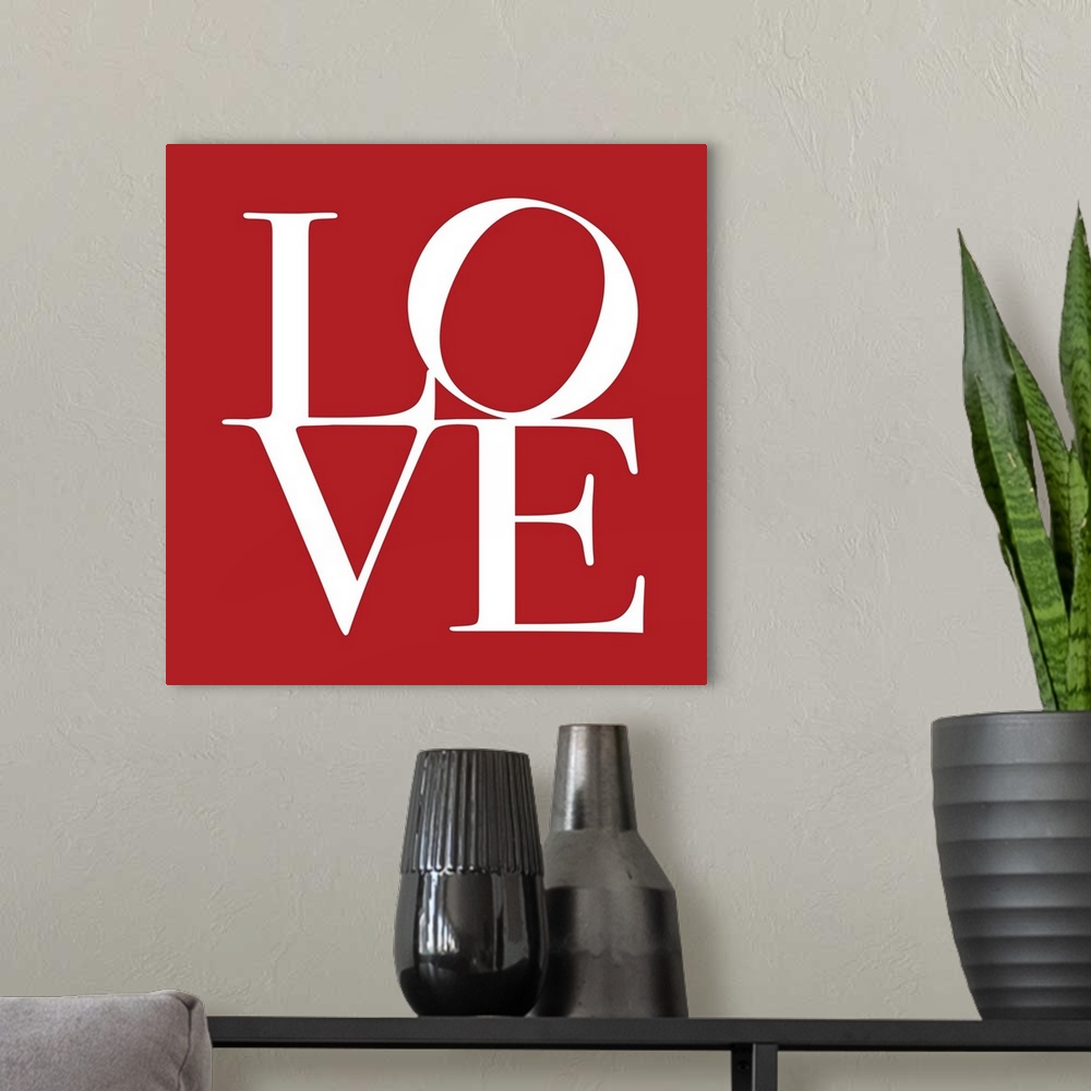 A modern room featuring Square art on a large canvas of the word "LOVE" with a tilted "O",  written against a solid red b...