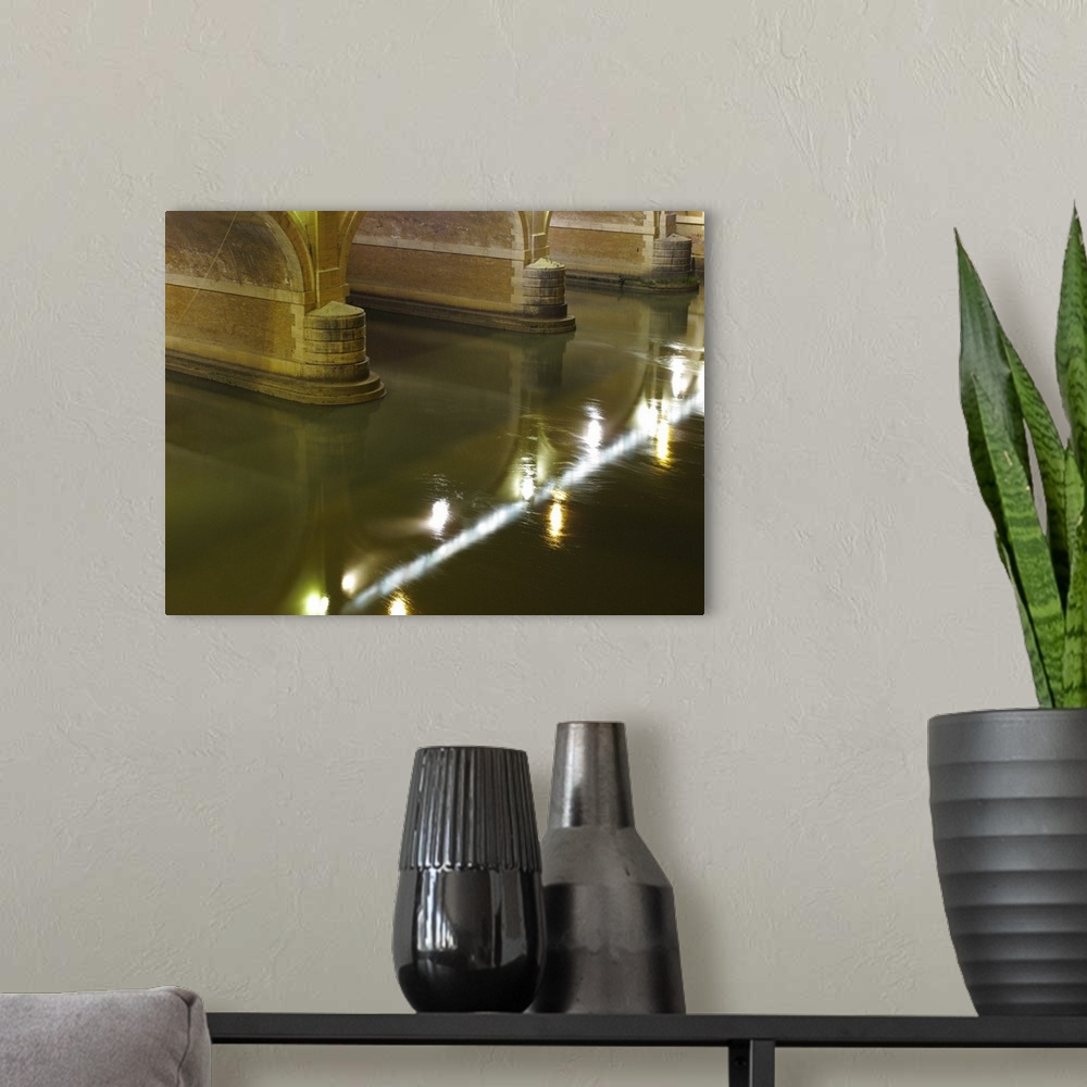 A modern room featuring Tiber river flowing under a bridge at night; Rome, Italy