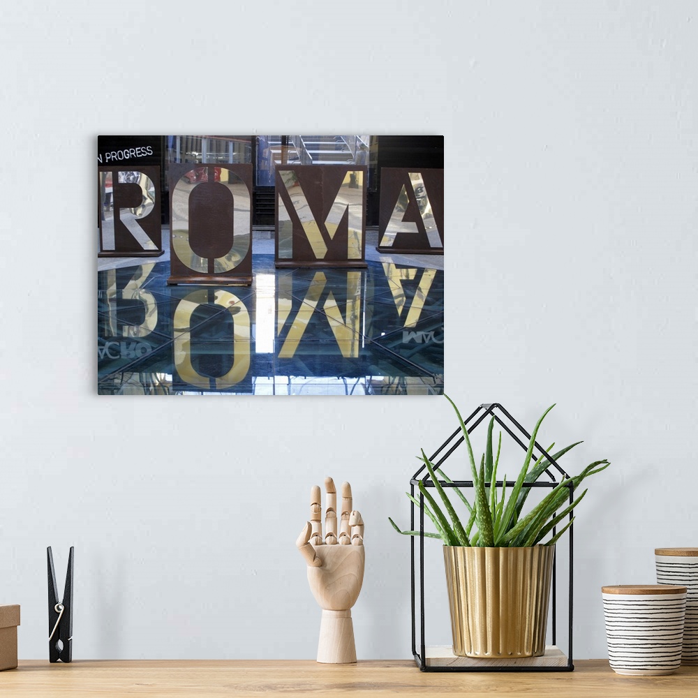 A bohemian room featuring An interior photograph of letters, that are the Italian spelling of Rome, cut into steel that are...