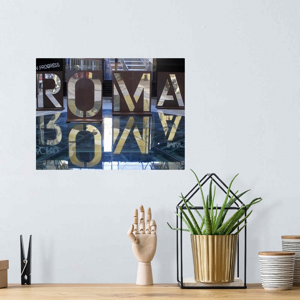 A bohemian room featuring An interior photograph of letters, that are the Italian spelling of Rome, cut into steel that are...