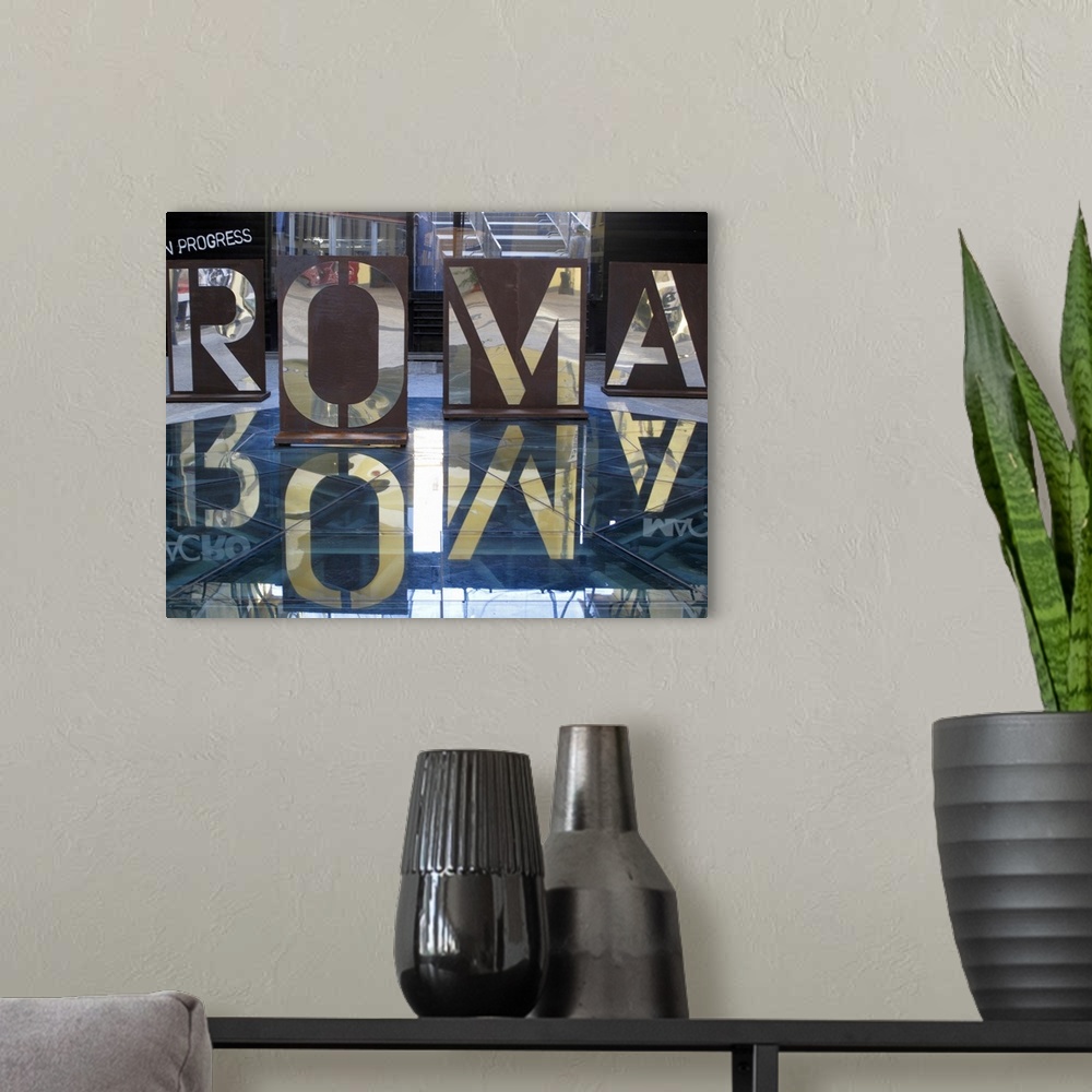 A modern room featuring An interior photograph of letters, that are the Italian spelling of Rome, cut into steel that are...