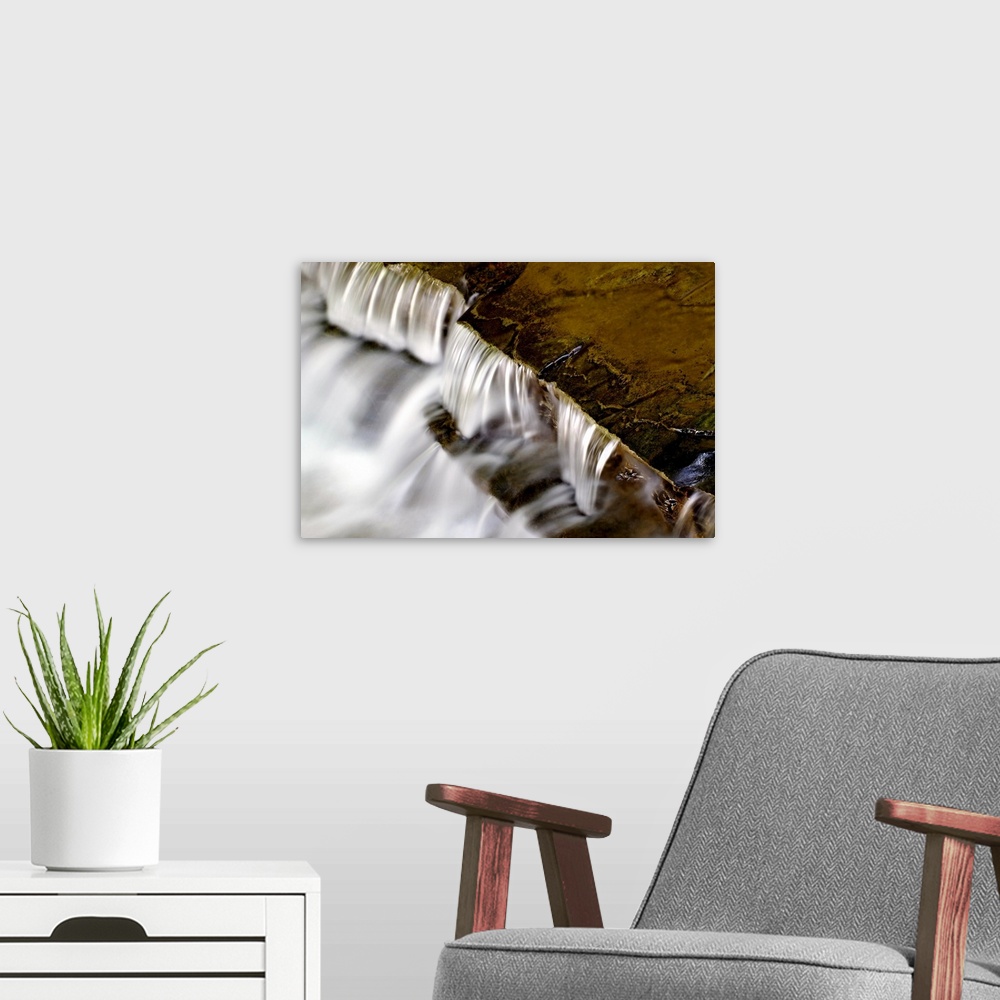 A modern room featuring Large photo print of water rushing downward off of rock formations.