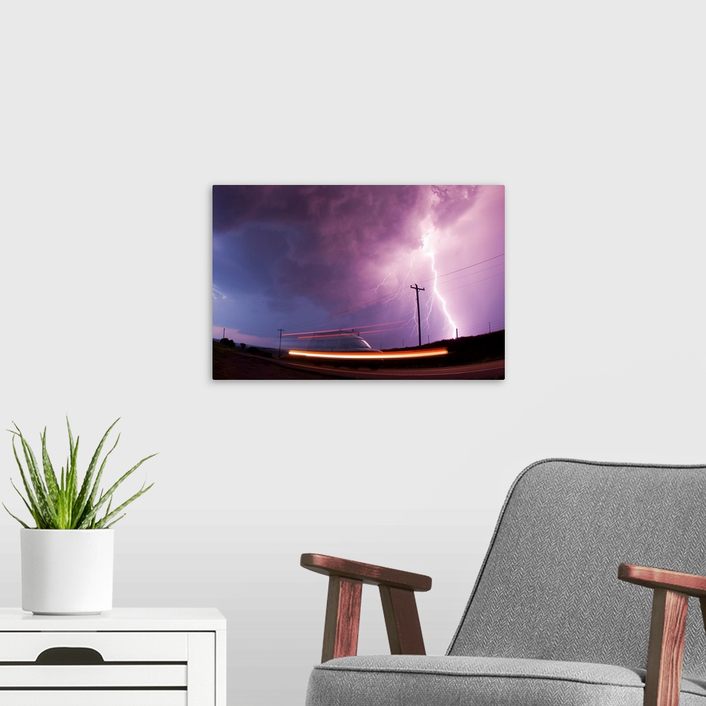 A modern room featuring A large lightning bolt strikes behind a storm chaser's moving van.