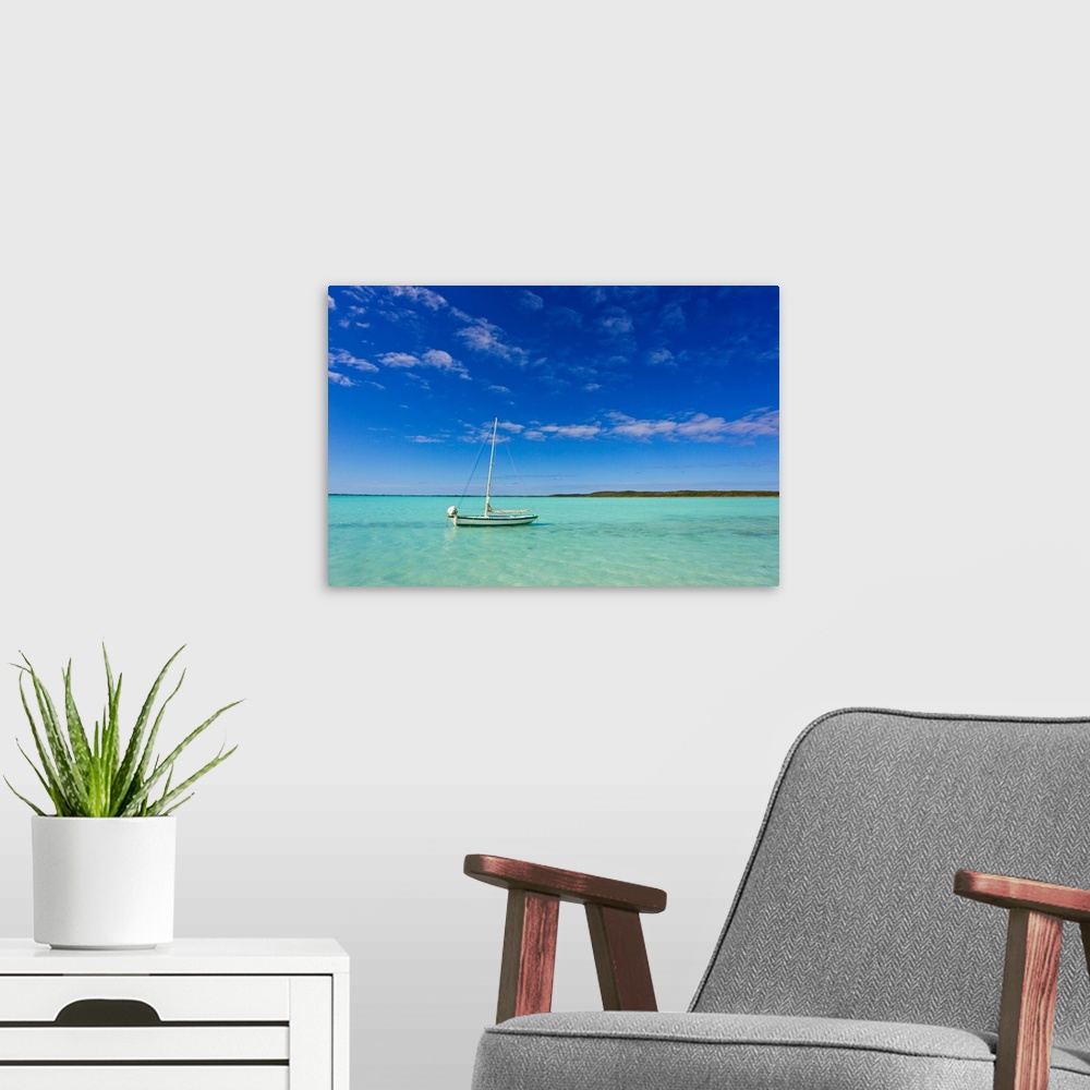 A modern room featuring A lone sailboat anchored in turquoise water.