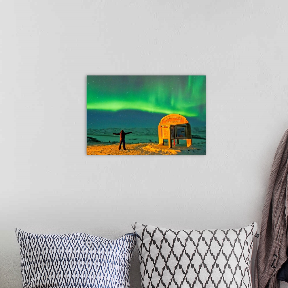 A bohemian room featuring A man looks in awe at the northern lights near the Arctic Circle sign.
