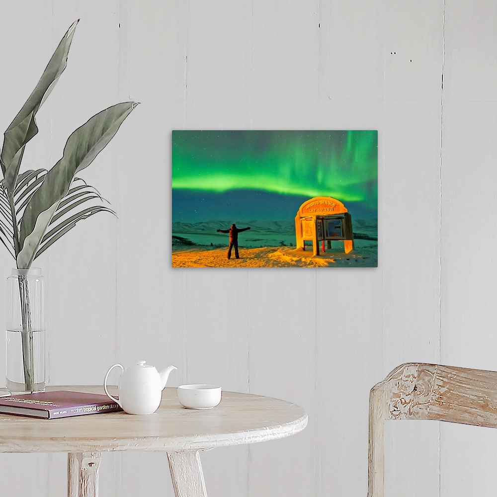 A farmhouse room featuring A man looks in awe at the northern lights near the Arctic Circle sign.