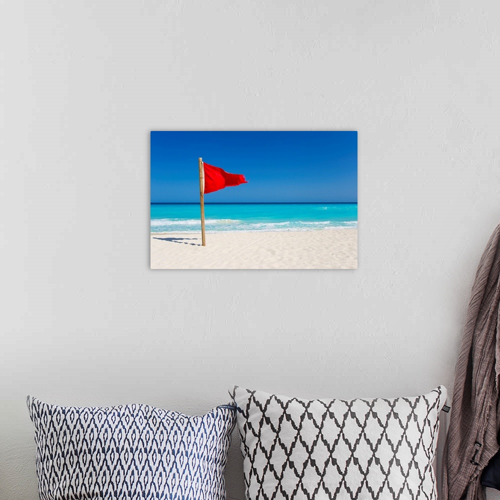 A bohemian room featuring A red flag is posted as a warning of caution on the beaches of Cancun, Mexico.