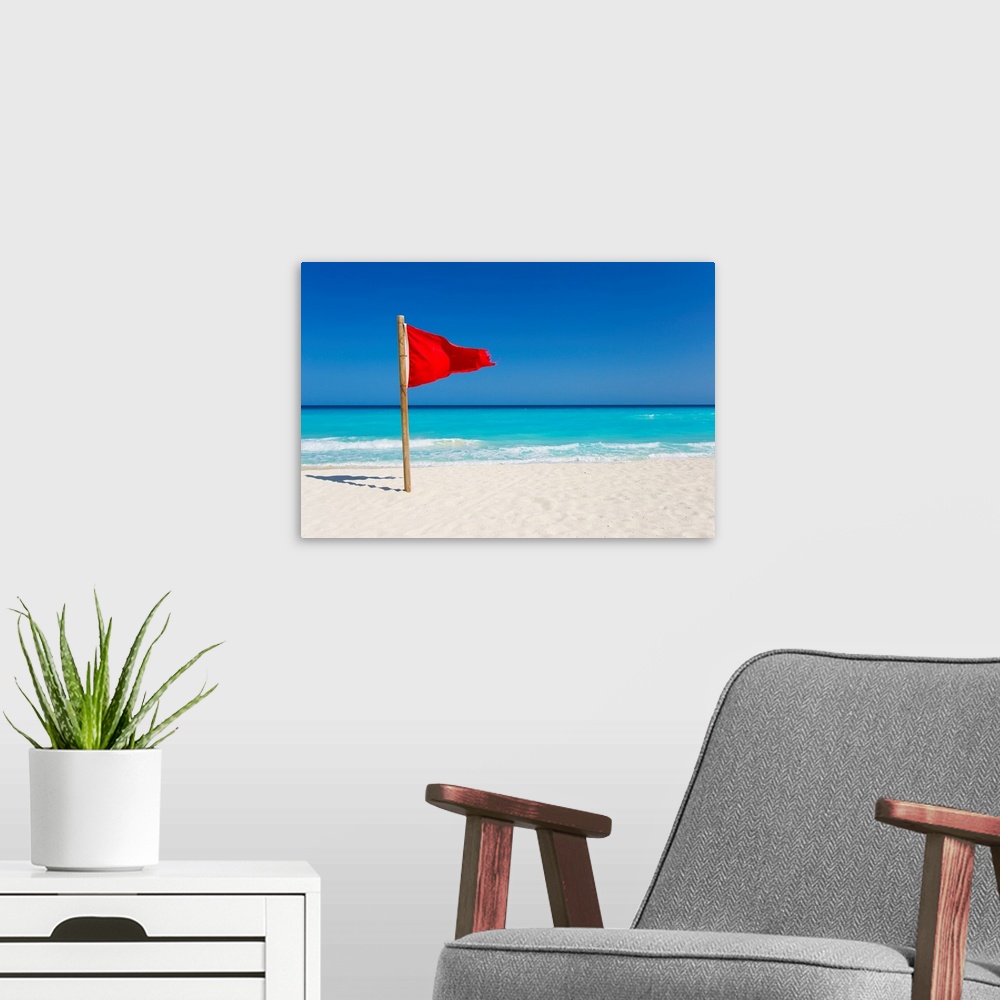 A modern room featuring A red flag is posted as a warning of caution on the beaches of Cancun, Mexico.