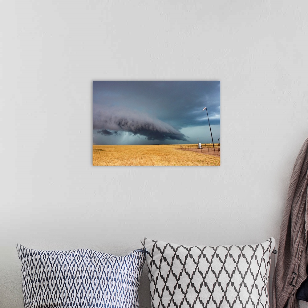 A bohemian room featuring A shelf cloud from a thunderstorm provides water to crops.