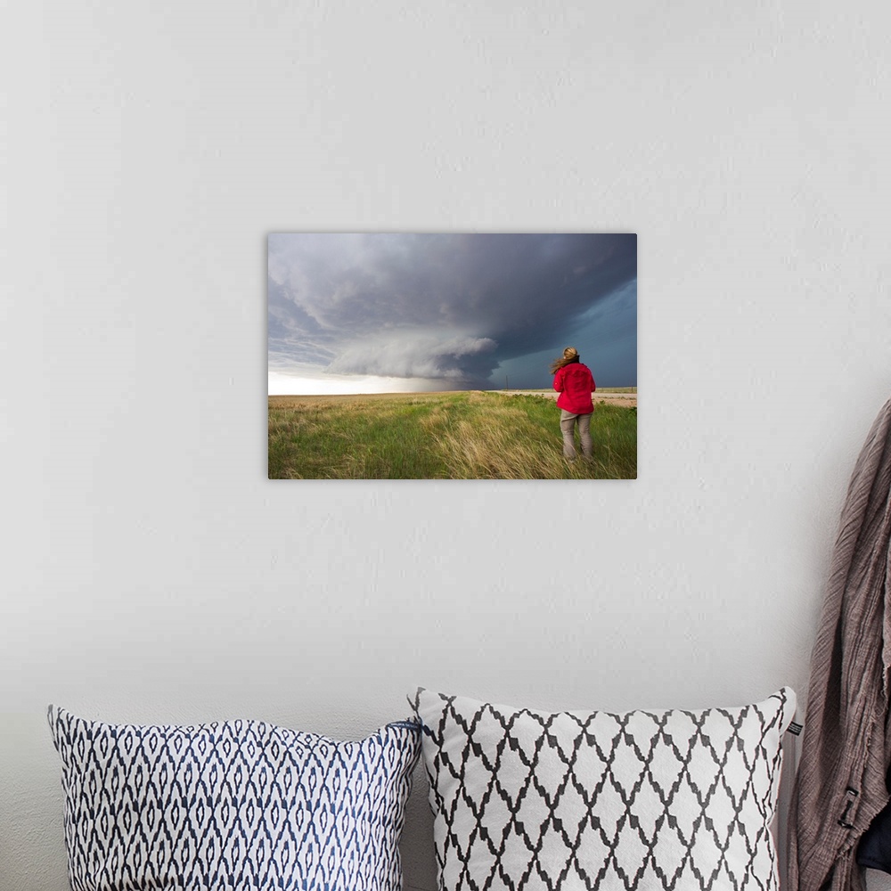 A bohemian room featuring A woman watches a massive wall cloud from a supercell thunderstorm.