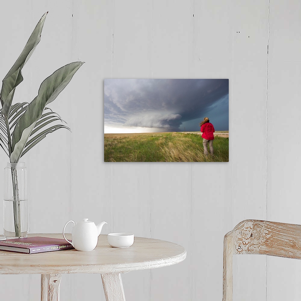 A farmhouse room featuring A woman watches a massive wall cloud from a supercell thunderstorm.