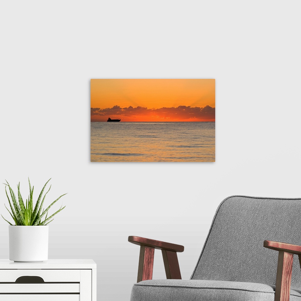 A modern room featuring A silhouetted ship moments before the sun rises over the horizon.