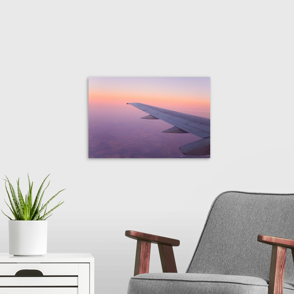 A modern room featuring Looking out and airplane window at sunset with a purple sky.