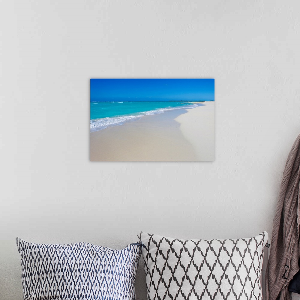 A bohemian room featuring A beautiful picture of teal colored ocean water coming up onto the white sand beach. A clear blue...