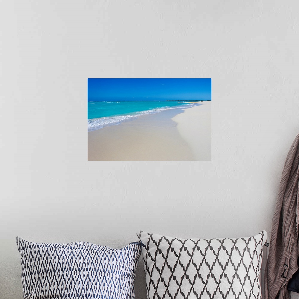 A bohemian room featuring A beautiful picture of teal colored ocean water coming up onto the white sand beach. A clear blue...