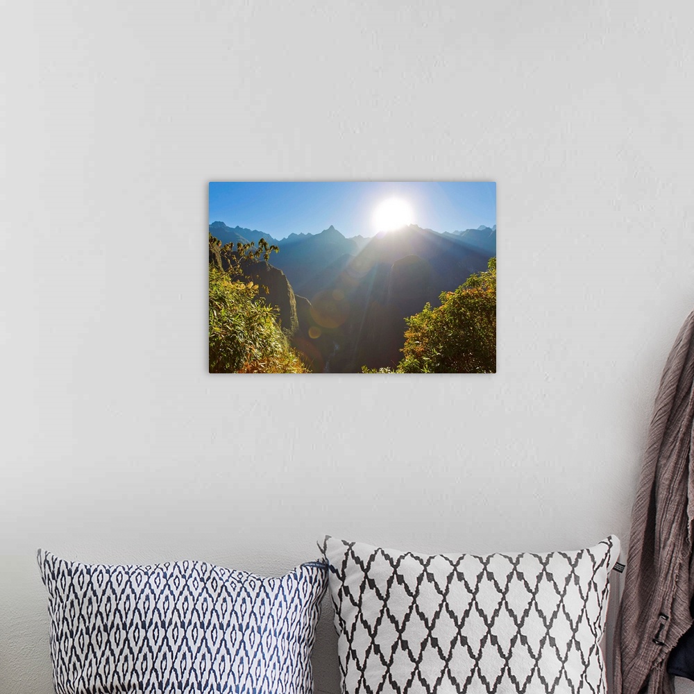 A bohemian room featuring Rays of sun shine through gaps in the Andes mountains at Machu Picchu.