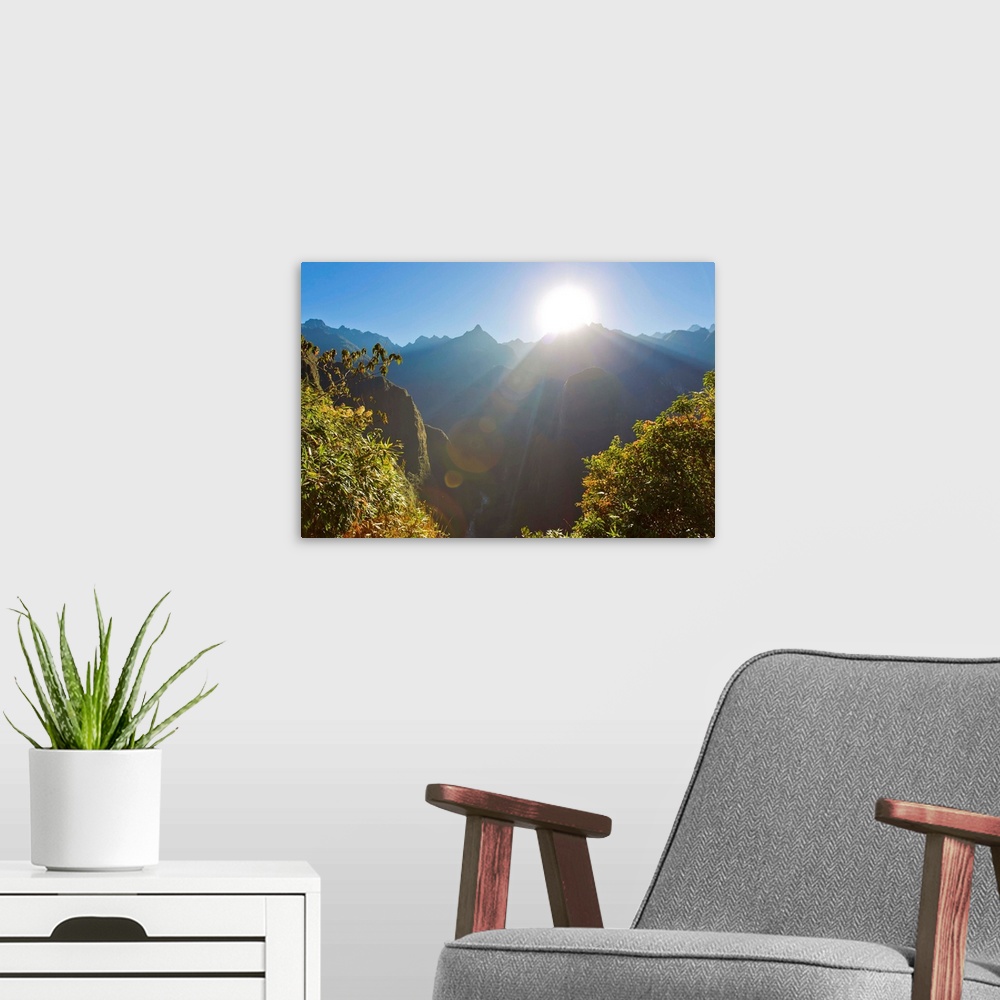 A modern room featuring Rays of sun shine through gaps in the Andes mountains at Machu Picchu.