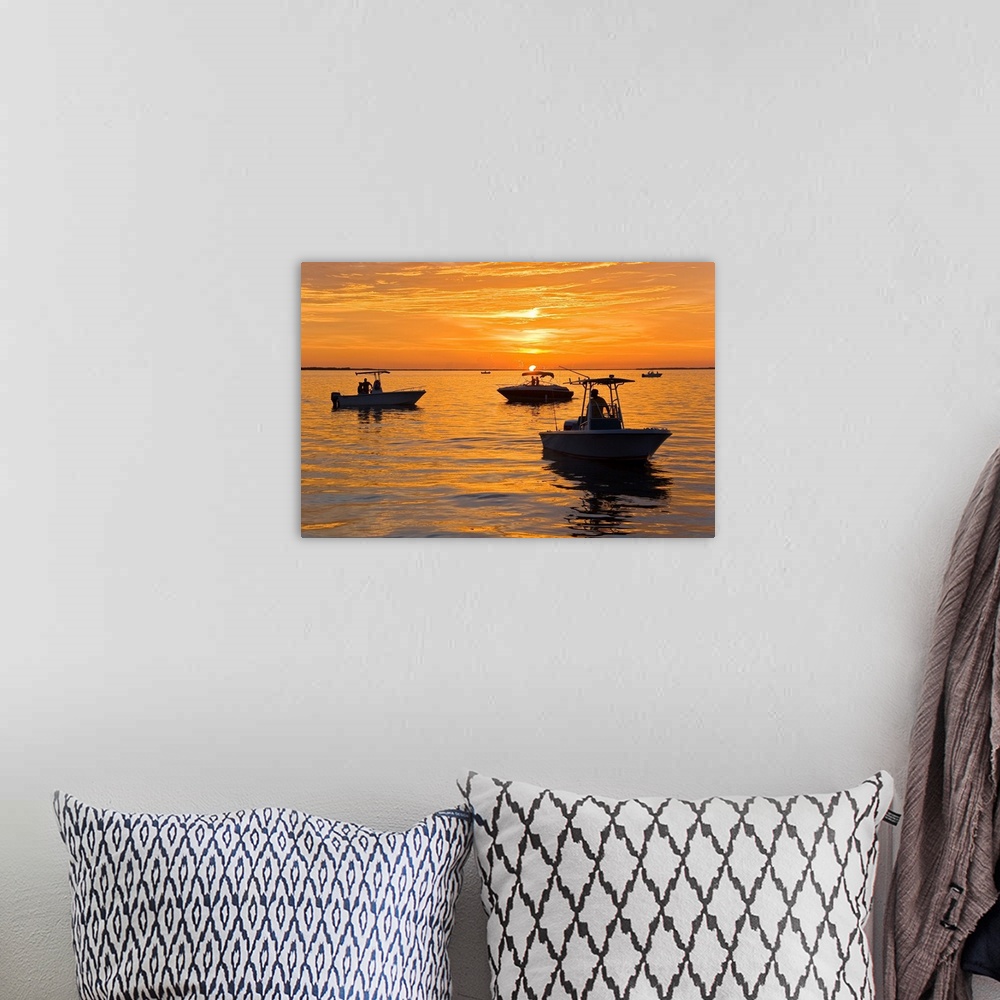A bohemian room featuring Silhouetted boats and shimmering water during a picture perfect sunset.