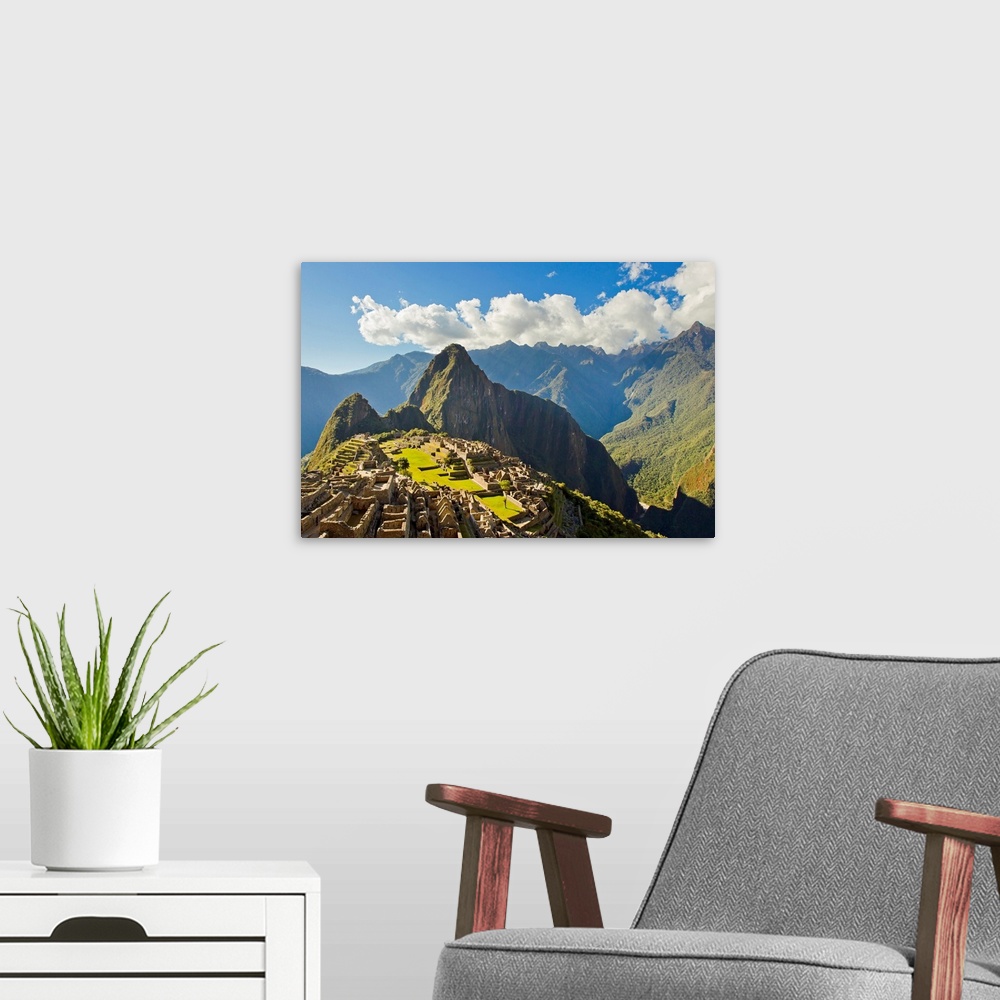 A modern room featuring Sun shining through the Andes mountains onto Machu Picchu at sunset.