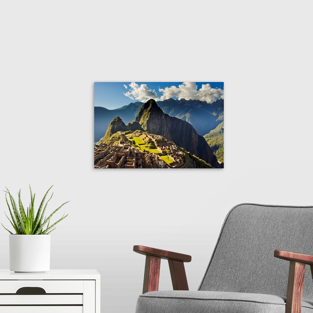 A modern room featuring Sun shining through the Andes mountains onto Machu Picchu at sunset.
