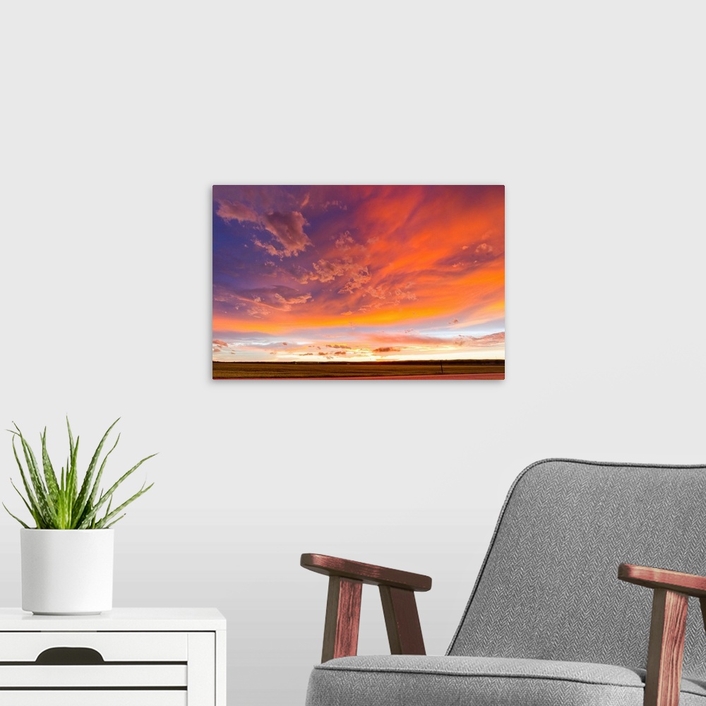 A modern room featuring The colorful backside of a thunderstorm lit up during sunset.