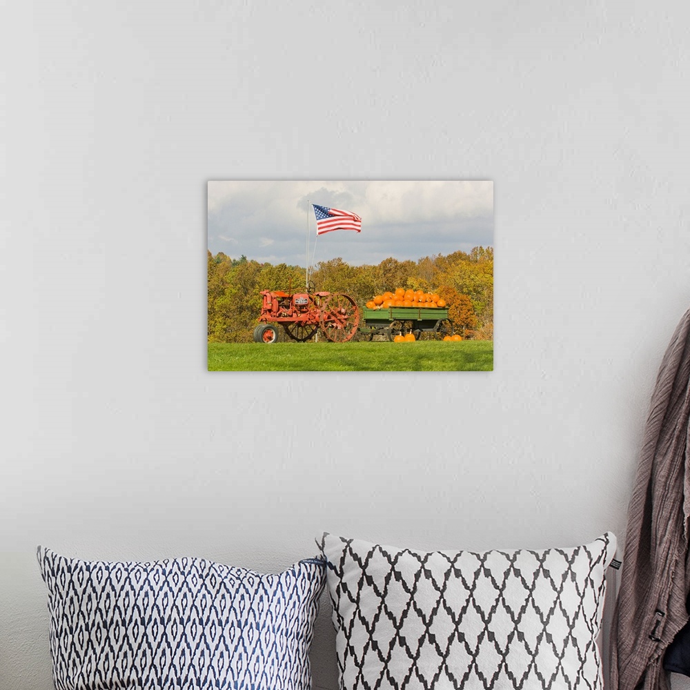 A bohemian room featuring The United States flag flying over tractor wagon filled with pumpkins.