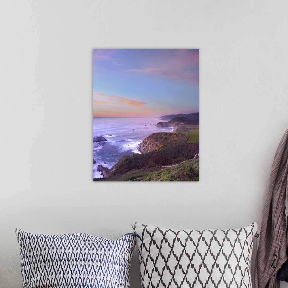 A bohemian room featuring Photograph of rocky cliff edge with crashing waves under a colorful cloudy sky.