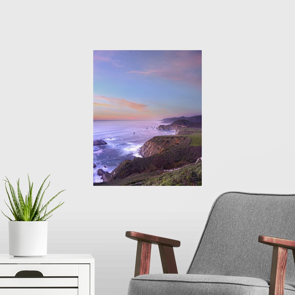 A modern room featuring Photograph of rocky cliff edge with crashing waves under a colorful cloudy sky.
