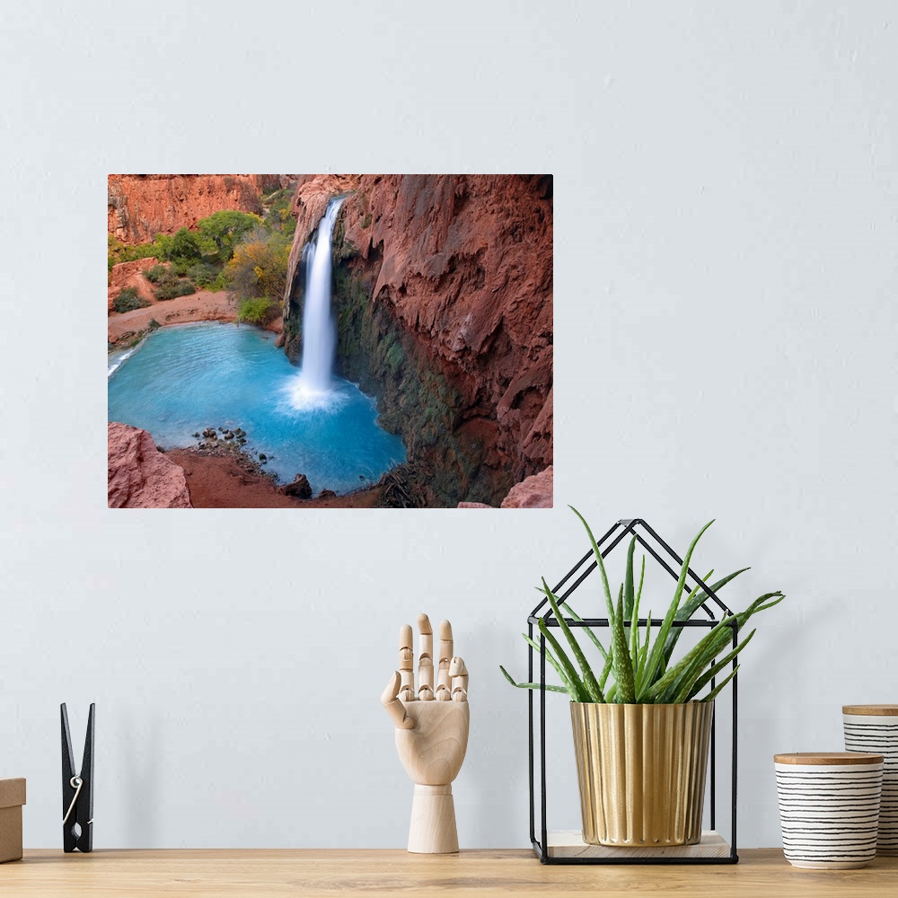 A bohemian room featuring Large photograph taken of a waterfall crashing into the clear water below.  This portion of the c...