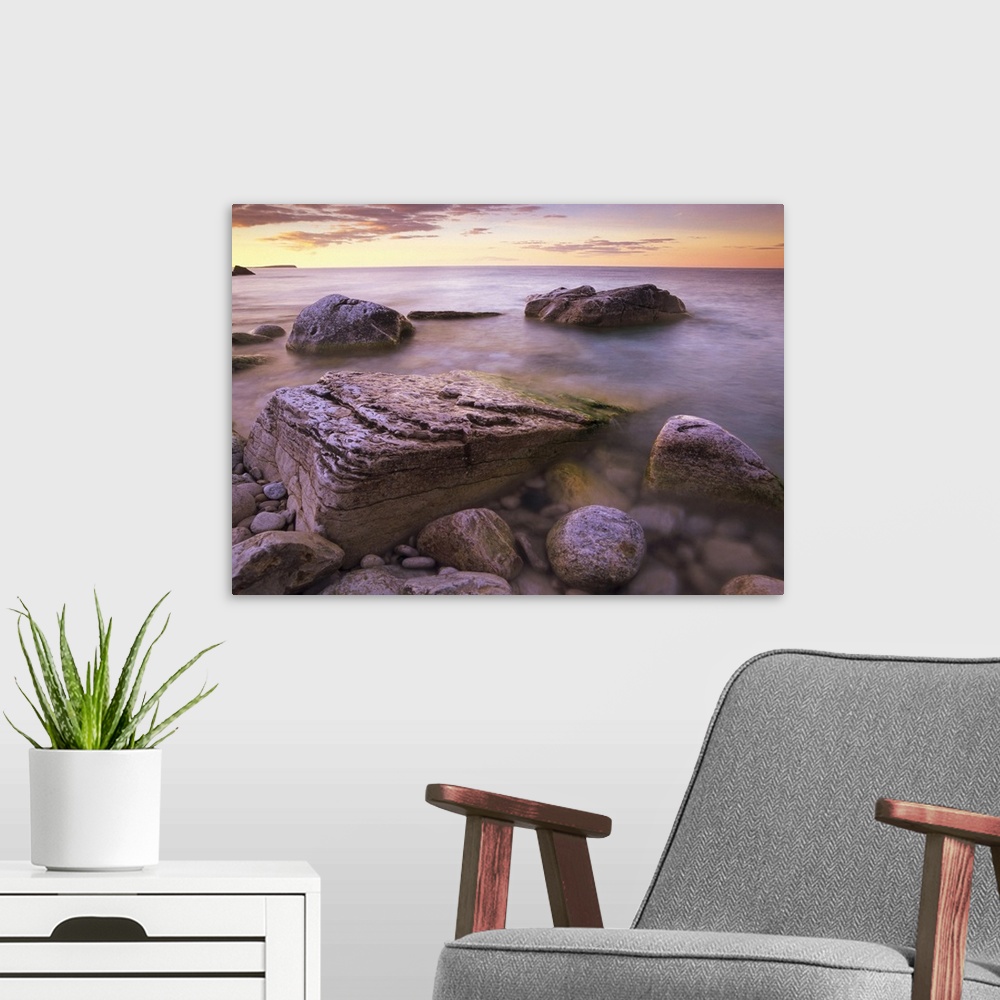 A modern room featuring Photograph of rocky shoreline filled with large boulders under a cloudy sky.