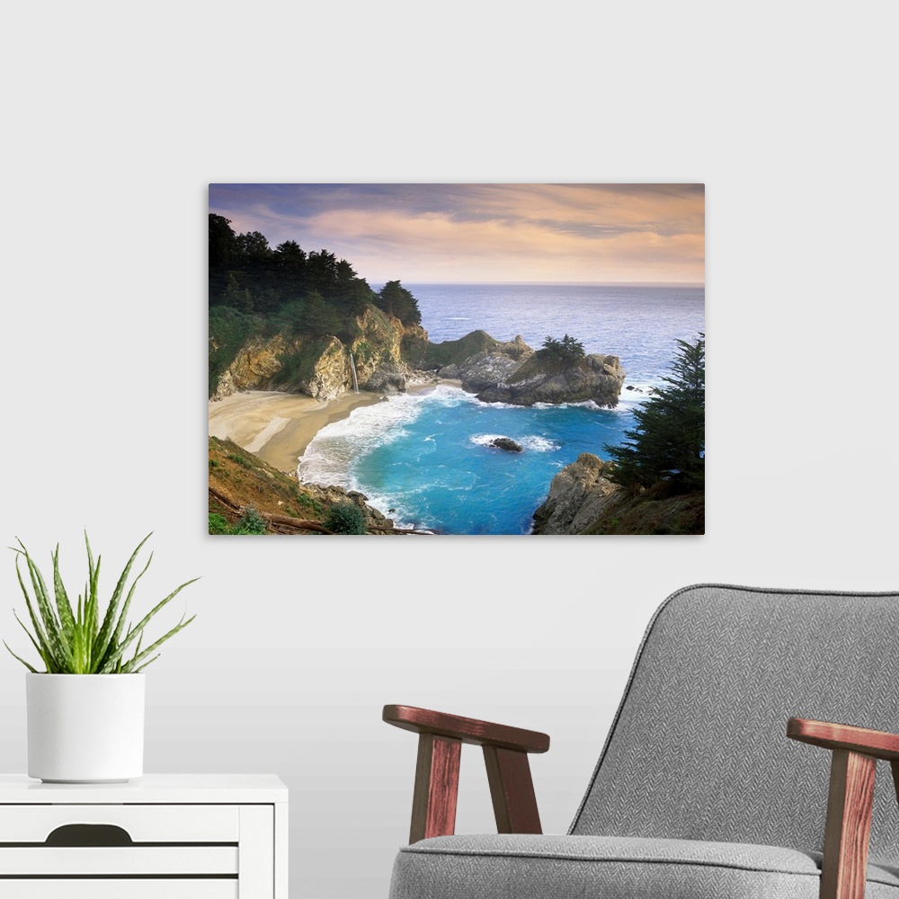 A modern room featuring This scenic photograph shows a rocky landscape surrounding a sandy beach and waves washing up on ...