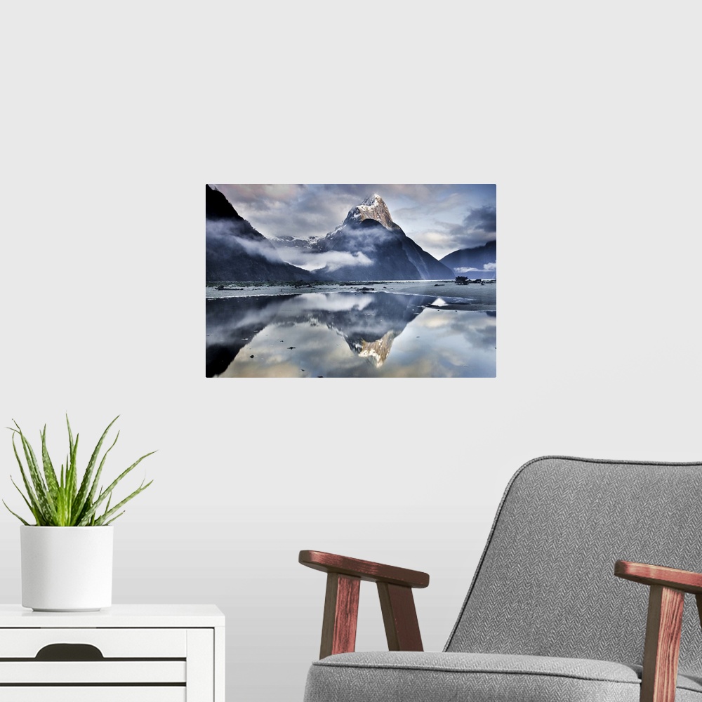 A modern room featuring A landscape photograph of a snow covered mountain peak and misty clouds reflecting in shallow bea...