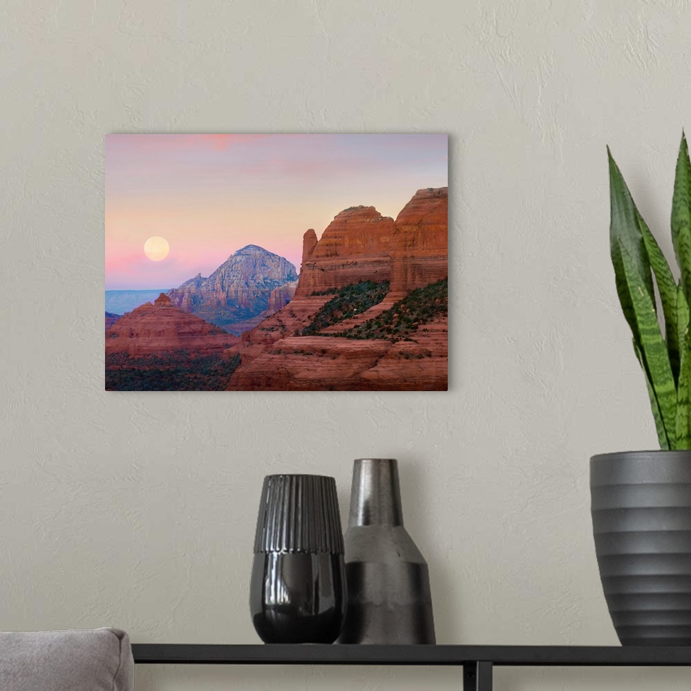 A modern room featuring Large, horizontal photograph of the moon setting in the early morning sky, over the large rock fo...