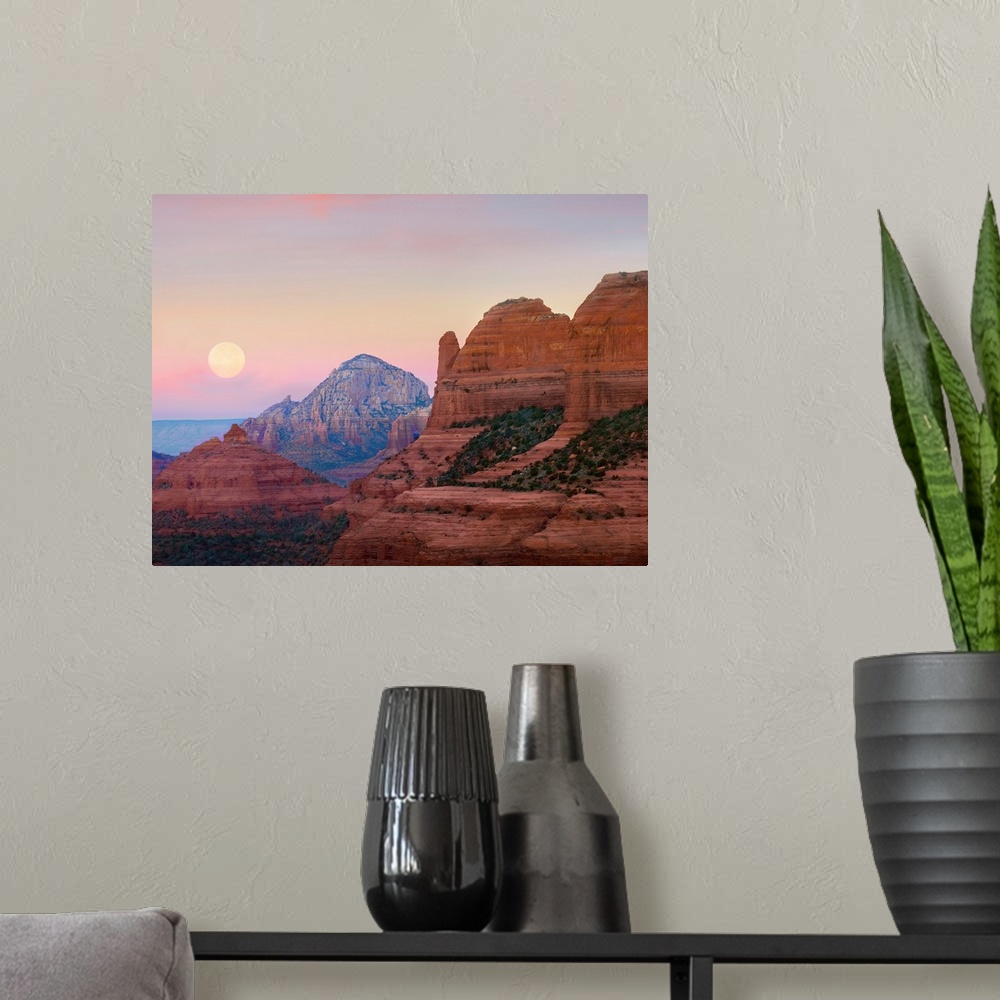 A modern room featuring Large, horizontal photograph of the moon setting in the early morning sky, over the large rock fo...
