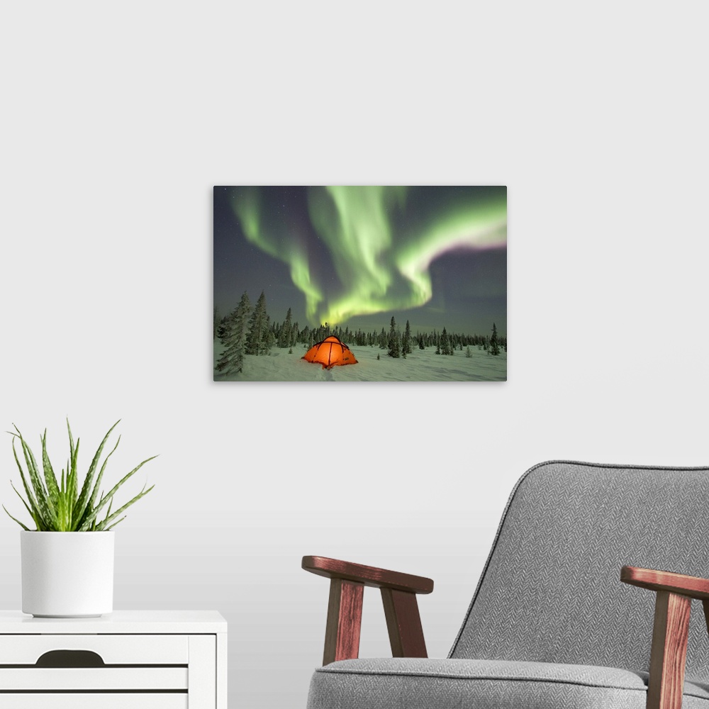 A modern room featuring This beautiful picture is taken of the northern lights over a campsite surrounded by snow covered...