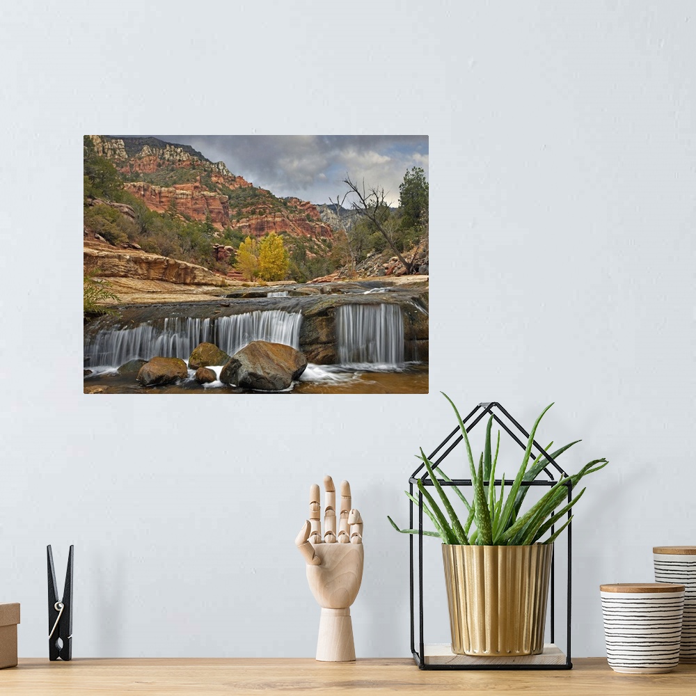 A bohemian room featuring Wall art of a small waterfall in a river with red rock formations in the background.