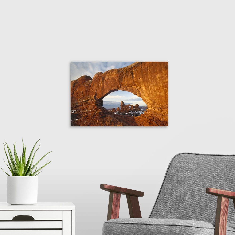 A modern room featuring Big canvas of a rock formation with a hole through it with another rock formation in the distance.