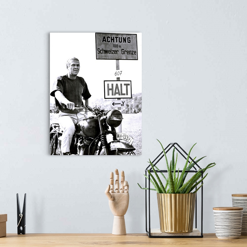 A bohemian room featuring Vertical movie advertisement for the 1963 film, The Great Escape.  A man sits on a vintage motorc...