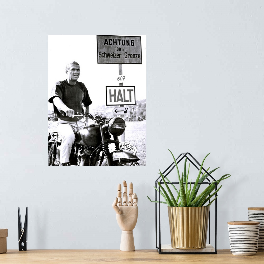 A bohemian room featuring Vertical movie advertisement for the 1963 film, The Great Escape.  A man sits on a vintage motorc...