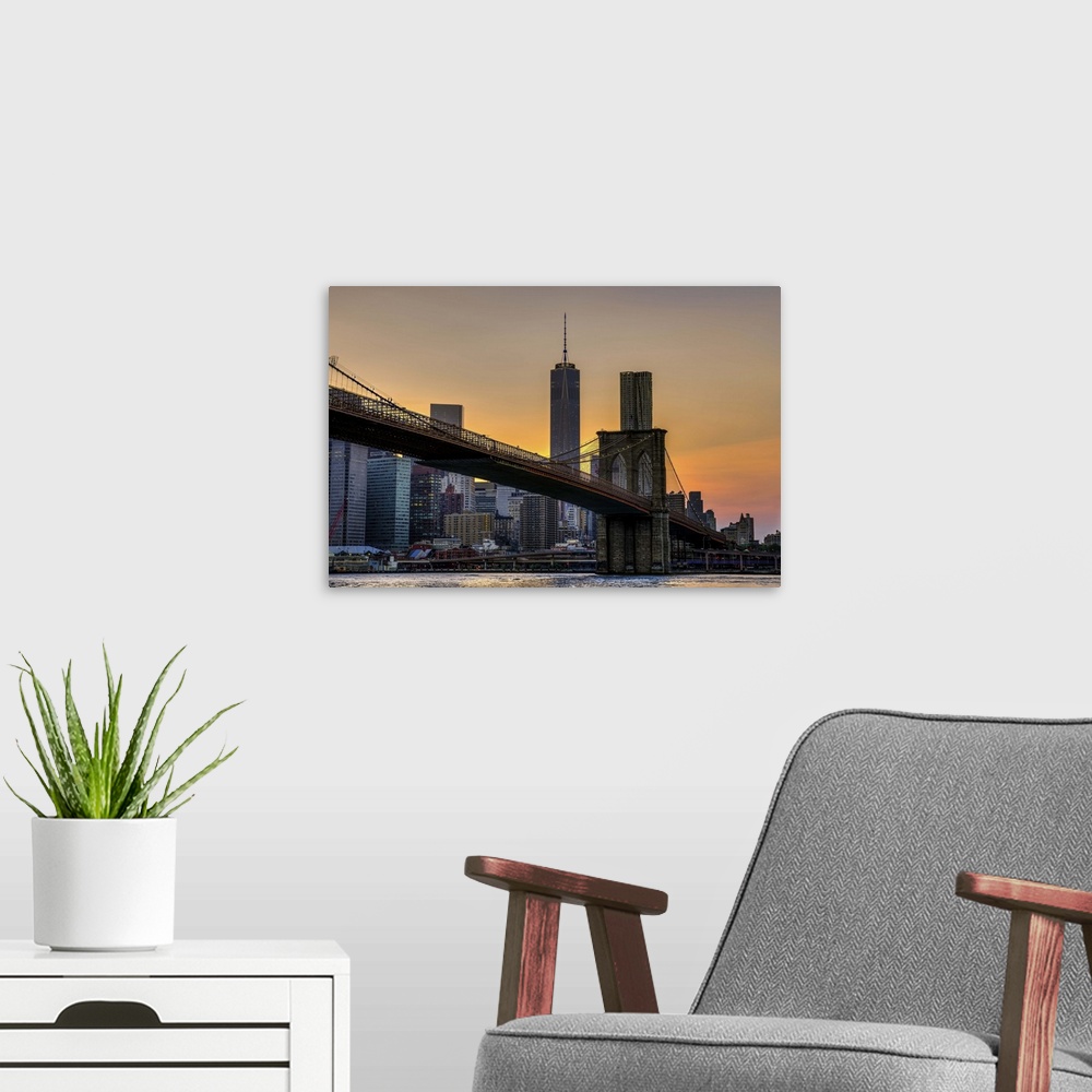 A modern room featuring A photograph of the Brooklyn bridge at twilight with One World Trade standing tall in the backgro...
