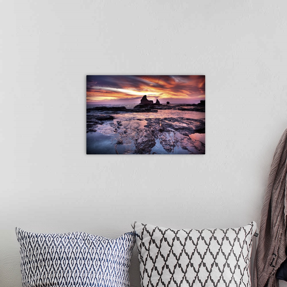 A bohemian room featuring A photograph of a dramatic coastal sunset scene.